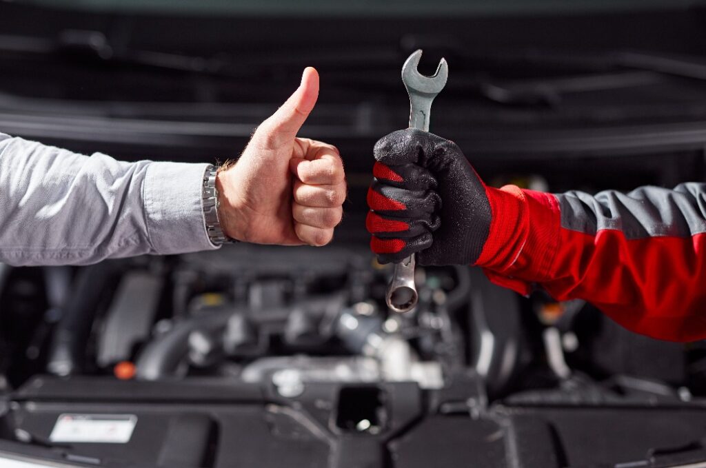 Ein Mann zeigt sich mit der Arbeit des Automechanikers in der Werkstatt zufrieden.