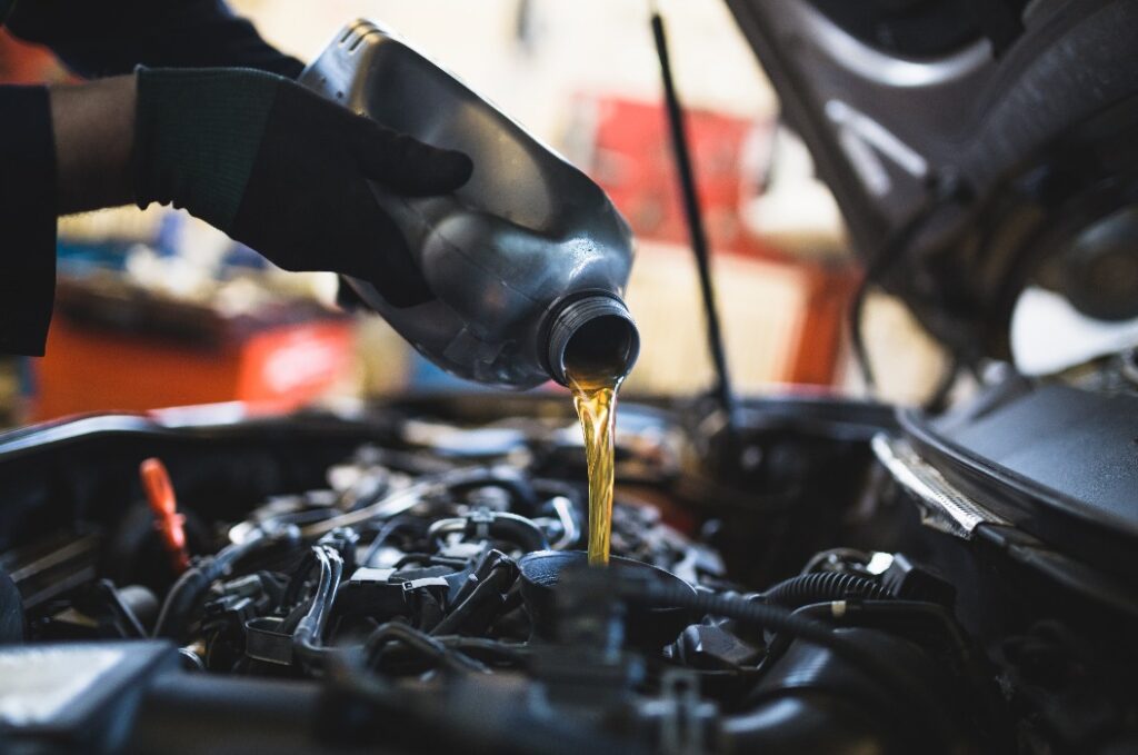Nahaufnahme der Hände eines unkenntlichen Mechanikers, der ein Auto wartet und Öl wechselt