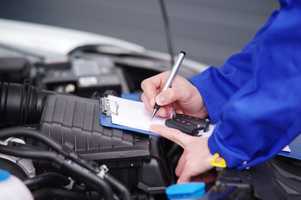 Mechaniker bei der Durchsicht eines Autos, TÜV-Untersuchung