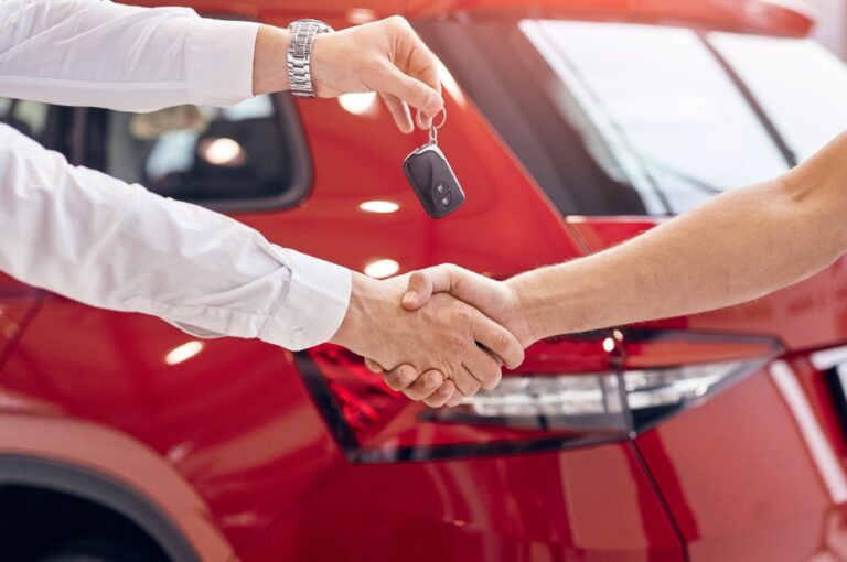 Crop-Händler mit Autoschlüssel schüttelt die Hand eines Kunden
