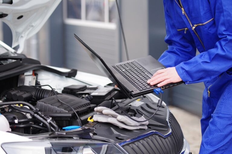 Mechaniker arbeitet mit einem Laptop an einem Auto, Motorsteuerung